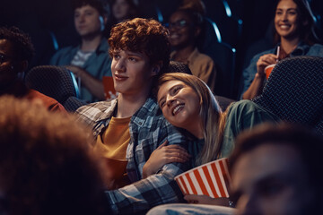 Young happy couple watching romantic movie in theater.