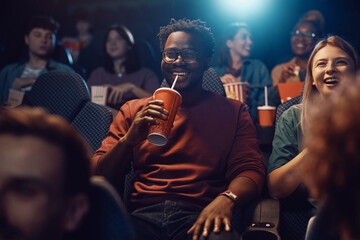 Happy black man watching movie in theater.