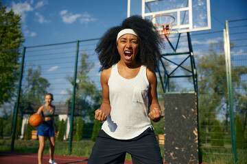 Excited young female basketball player screaming while looking at camera