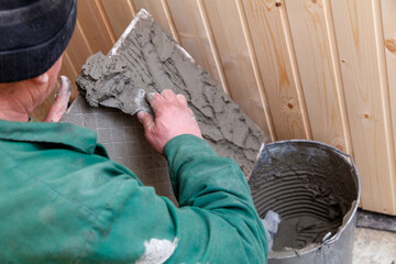A man is laying cement on a wall