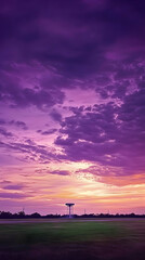 Obraz premium Purple Sunset Paints Sky Over Field with Distant Tower