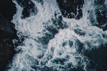 Aerial view Ocean waves crashing against dark rocks, background sky, nature texture