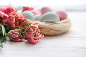 Bouquet of tulips and nest with Easter eggs in soft pastel colors on white background