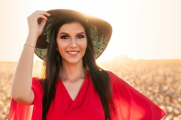 Woman in red dress and hat in sunlit field