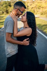 Young couple embracing on a sunlit road.