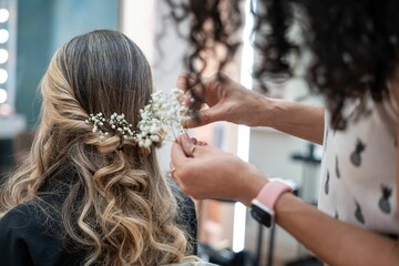Hairstylist creating a bridal hairstyle with flowers.