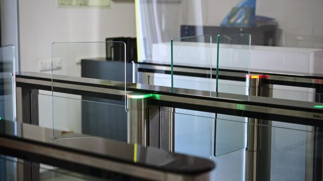 Passing through a turnstile into an office building. Office workers enter and exit through a modern turnstile, using a key card to enter.