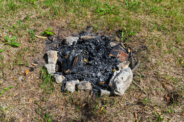 Fire pit remnants after a summer gathering in a grassy outdoor area