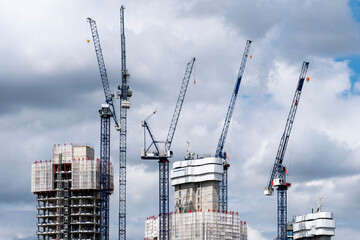A construction site dominated by cranes working against a backdrop of dramatic clouds, emphasizing growth and the evolution of the urban landscape in modern cities in London UK