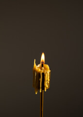Close-up of a burning candle with melted wax dripping down its sides on dark background