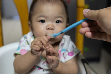 Cute baby girl eating first food