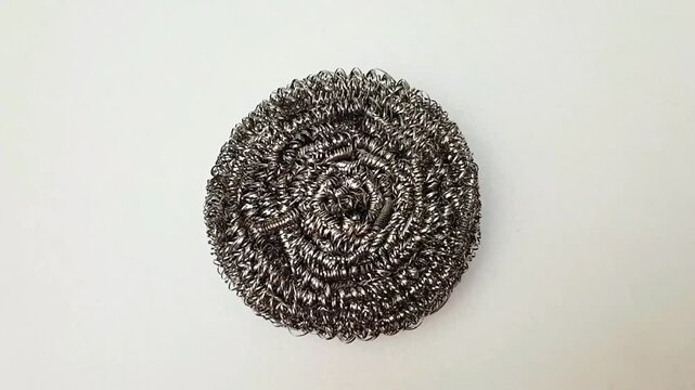 Stainless steel scrubber, metal pot sponge isolated rotating on white background, steel wool scouring pad for washing dishes, scrub bud, top view