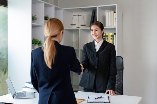 Lawyer warmly shaking hands with a client in a modern office after finalizing a legal agreement