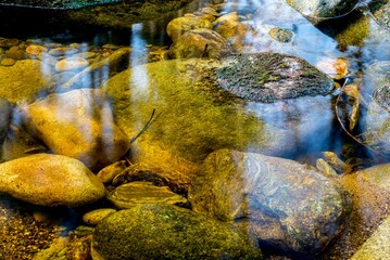 Obraz premium Close-up of colorful stones under clear water with reflections in a serene stream.