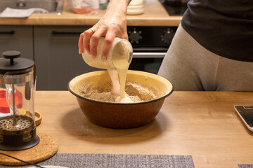 Woman adding ingredients together to prepare dough. Baking