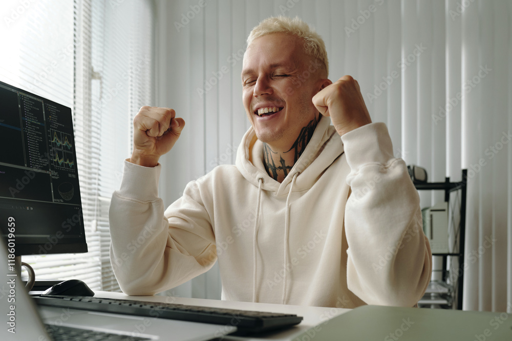 Poster programmer achieving success in his work while sitting at his workplace with computer