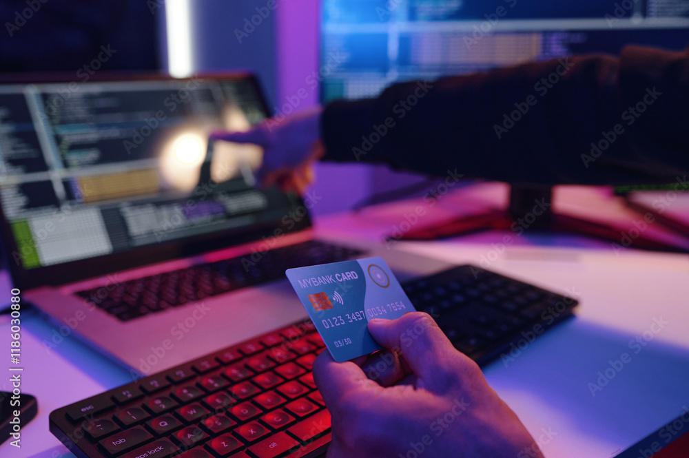Poster close-up of it worker checking data of credit card on computer during his work in dark office