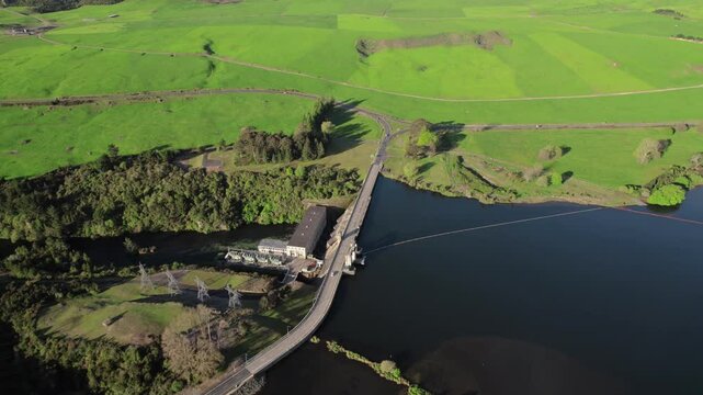 Aerial Whakamaru bridge crossing dam with lush green fields in Waikato, New Zealand