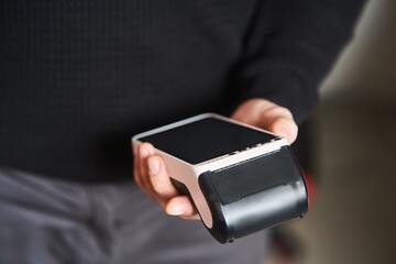 Bank terminal for contactless payment. Acquiring. Young man holds a terminal in his hands.