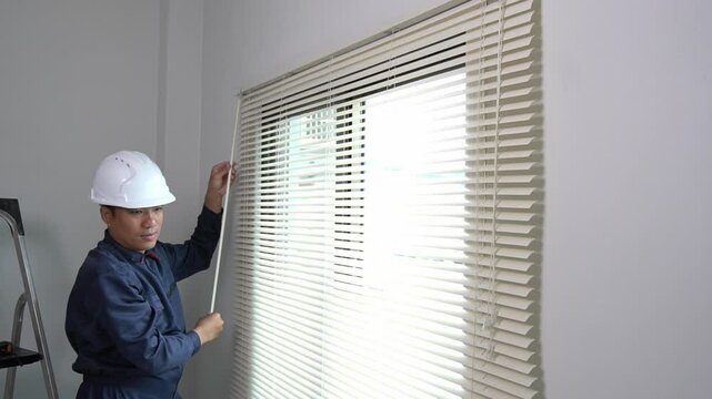 Asian technician installs sunshades on windows in the house, furniture installation or home decorating concept.