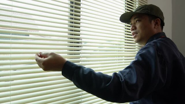 Asian worker installs sunshade on window in house, furniture installation or home decoration concept.