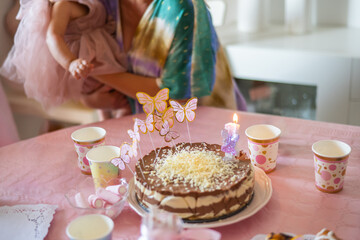 Delicious birthday cake adorned with butterfly-shaped toppers and a lit candle creating a sweet, festive atmosphere at a baby girl's first birthday celebration