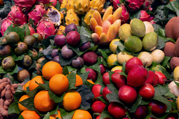 Assortment of exotic fruits, including dragon fruit, mangosteen, papaya, and passion fruit, displayed at a market.