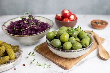 A bowl with variety of fermented foods: marinated green olives, cucumber, red cabbage, pickles.
