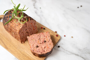 Close-up of liver pate slices on a wooden cutting board with spices.