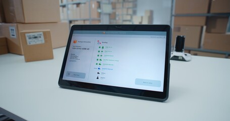 Postal Service Employee Scans Code on Cardboard Box with Barcode Scanner, Checks Parcel Information. Tablet Computer Screen Shows Delivery Tracking App to Monitor Package Routing to Client. Close Up.