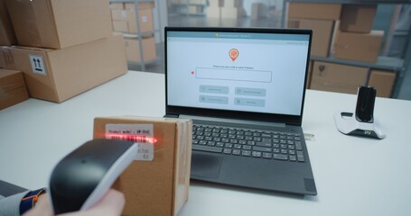 Close Up of Inventory Manager Scanning Code on Cardboard Box with Barcode Scanner, Checking Parcel Information. Laptop Display Shows Delivery Tracking App for Monitoring Package with E-Commerce Orders