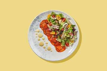 A vibrant and refreshing salad featuring thinly sliced gravlax salmon, fresh greens, and citrus fruits. The dish is garnished with crumbled feta cheese