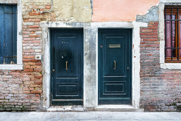 Ancient wooden door in old stone home wall in Venice. Italy. Old blue wooden doors in an ancient Venetian house in Venice, Italy.