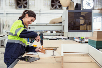 Professional women staff worker assembly wood furniture product in factory with safety suit