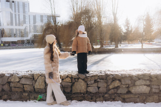 Family winter walk in the forest. Raising a child, family habits. Mother and daughter are having fun in winter in the forest in sunny frosty weather. A mother's hug.