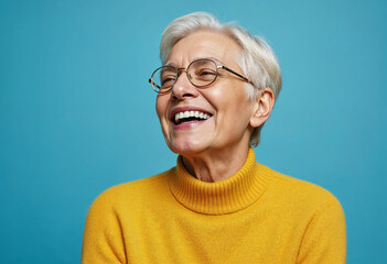 Portrait of a gray-haired mature woman in a yellow sweater on a blue background