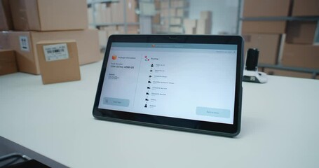 Postal Service Employee Scans Code on Cardboard Box with Barcode Scanner, Checks Parcel Information. Tablet Computer Screen Shows Delivery Tracking App to Monitor Package Routing to Client. Close Up.