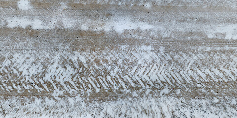 panorama top view from above on texture of snow covered gravel dirt road with tractor tire tracks...