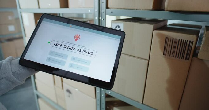 Postal Warehouse Associate Scans QR Code on Cardboard Box with Barcode Scanner, Checks Parcel Information. Tablet Computer Screen Shows Delivery Tracking App to Monitor Package Routing. Close Up.