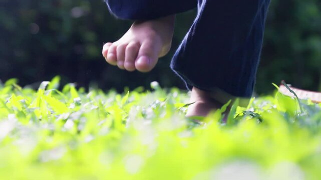 A little child is exercising in the park barefoot, jumping and stomping their feet