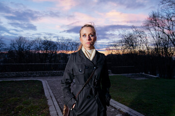 Woman Standing Outdoors at Sunset Wearing a Coat and Scarf..