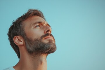 Obraz premium A Man Gazing Upward Hopeful and Peaceful, Contemplative Portrait Against a Serene Light Blue Sky
