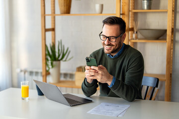 Man using smartphone and laptop computer for electronic banking, making reservation, online shopping