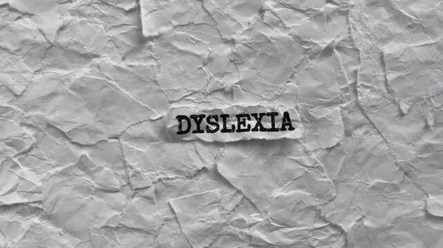 Crumpled piece of paper with word Dyslexia on torn white paper pieces background. Zoom in.