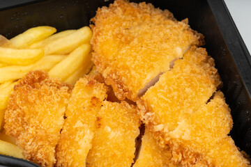 Breaded chicken with french fries take away closeup, roasted breaded meat fillet
