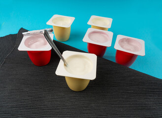 Yogurt cups set, pink and yellow fruit yoghurt in plastic pots, milk pudding container with spoon