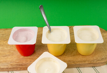 Yogurt cups set, pink and yellow fruit yoghurt in plastic pots, milk pudding container with spoon