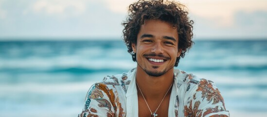 Happy biracial man with curly hair smiling at the beach during sunset with serene ocean in background and ample copyspace for text