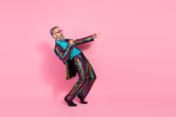 Fototapeta premium Stylish mature man in vibrant suit dancing on a pink background conveying energy and charisma
