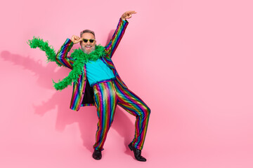Stylish senior man in colorful costume against pink background posing joyfully